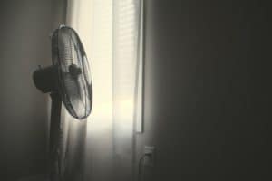 black and white photo of a fan pointing toward a curtained window