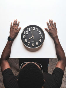 image of a man sitting at a table with a clock in front of him on the table