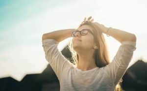 woman with her hands on her head relaxing outside in the sun