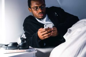 man lying in bed looking at his phone